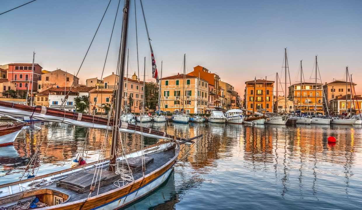 The harbour marina of La Maddalena in Sardinia in the evening with boats and colourful townhouses
