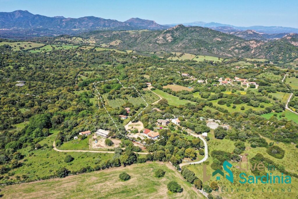 Aerial view of rural resort set in ever green countryside with granite hills on the background 