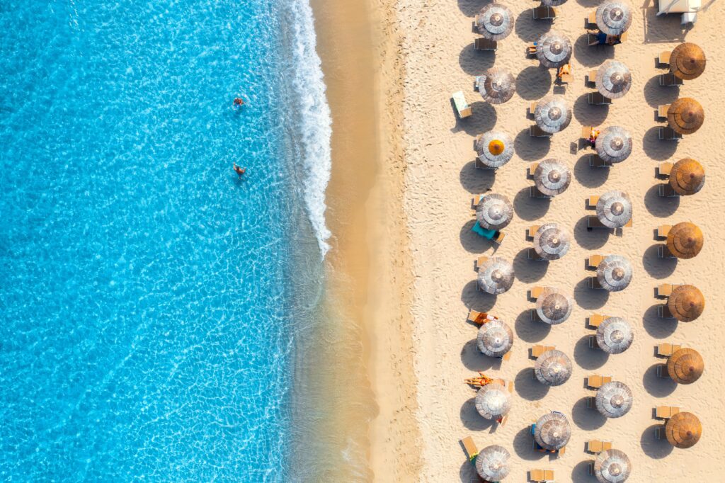 aerial view of sandy beach with umbrella and turquoise sea waters in sardinia