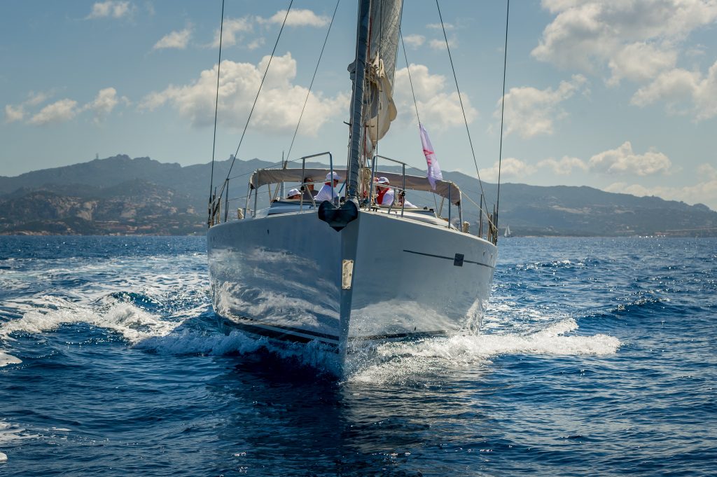 FRONT OF  LUXURY YACHT CRUISING  A BLUE AZURE SEA AND MEDITERRANEAN COATLINE AT THE BACK 